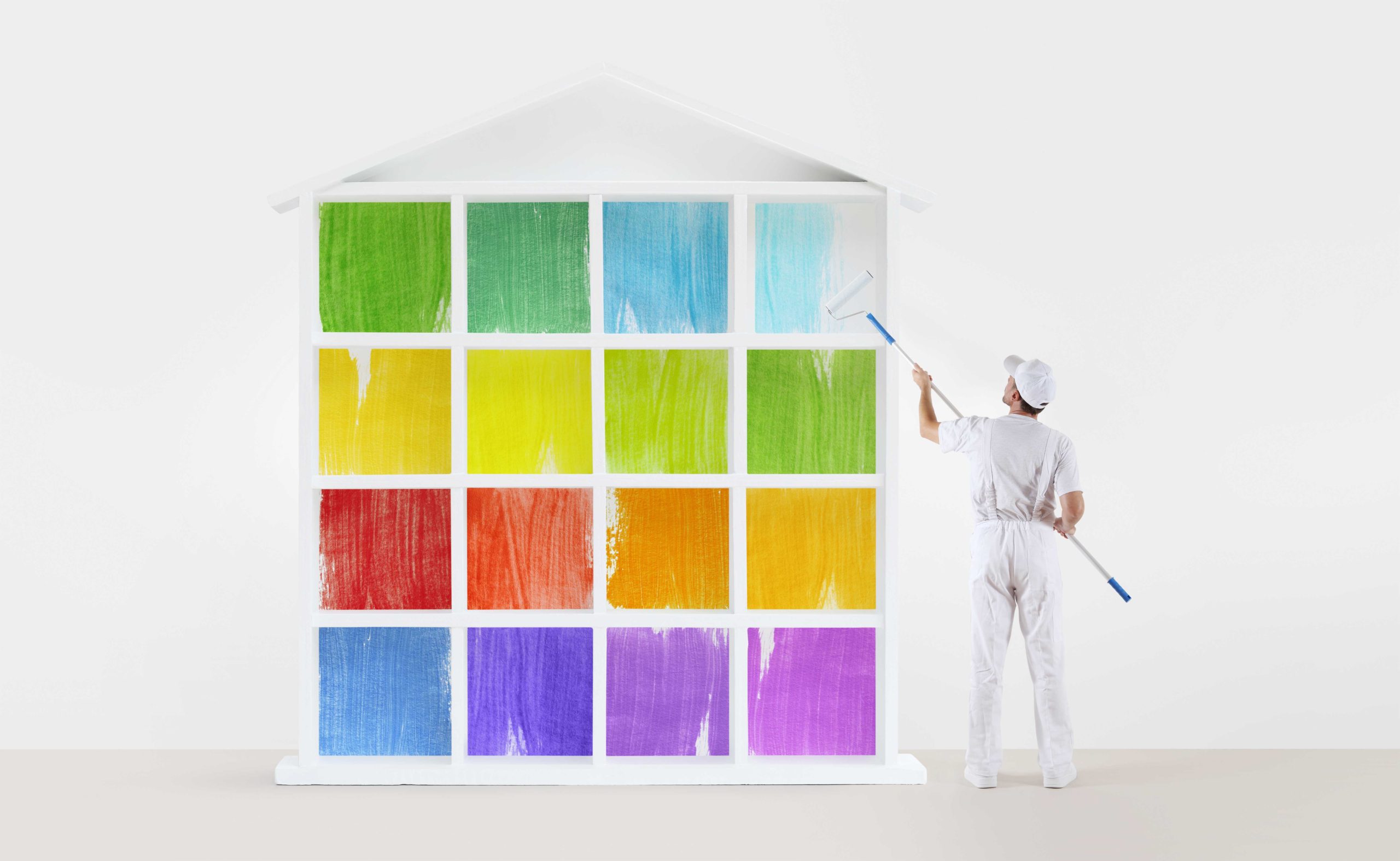 home service concept. painter man with paint roller, painting a colors house model isolated on the blank wall background